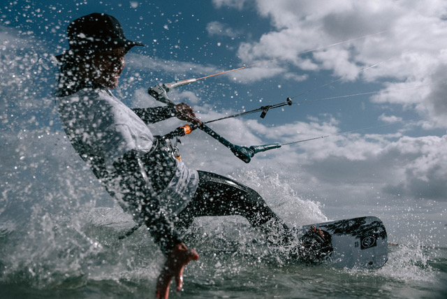 Kitesurf-Instructor fährt dynamisch durch Spritzwasser