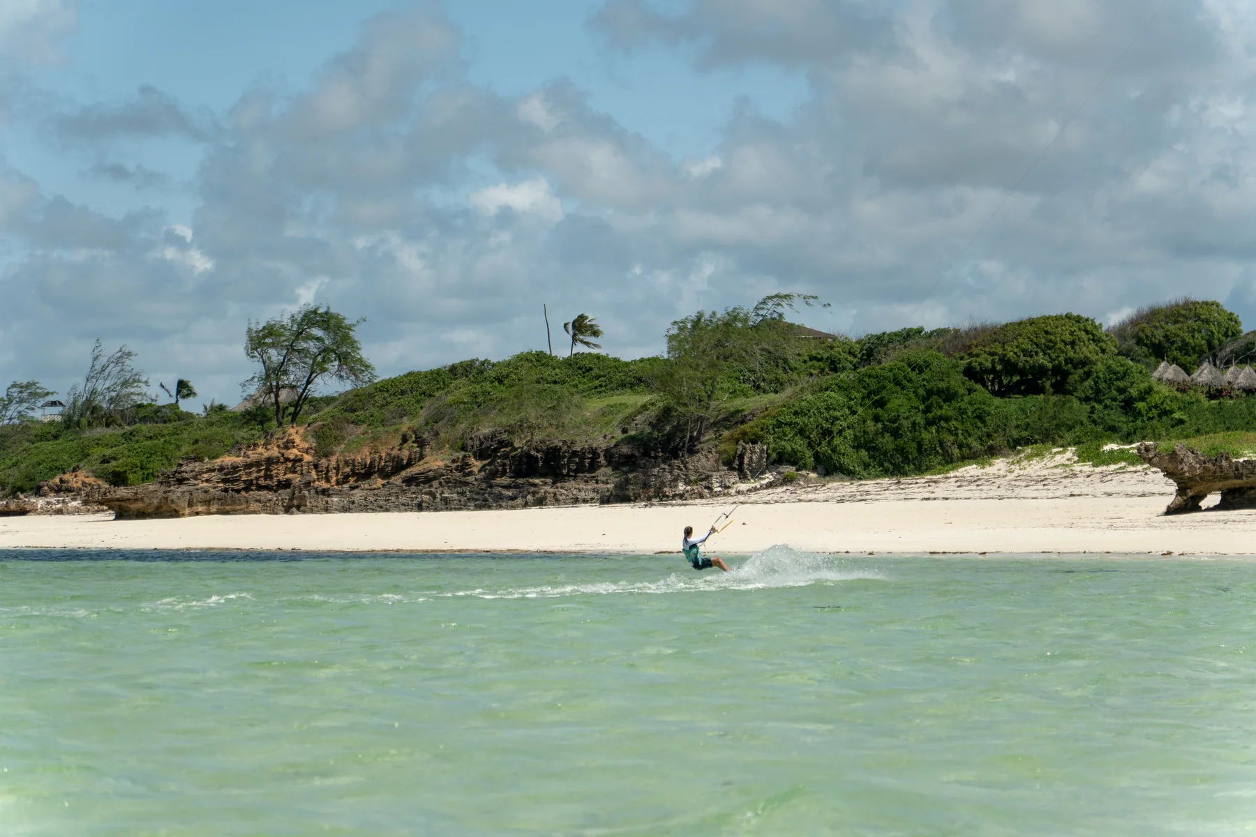 Kitesurfer fährt durch das türkise Flachwasser von Watamu in Kenia